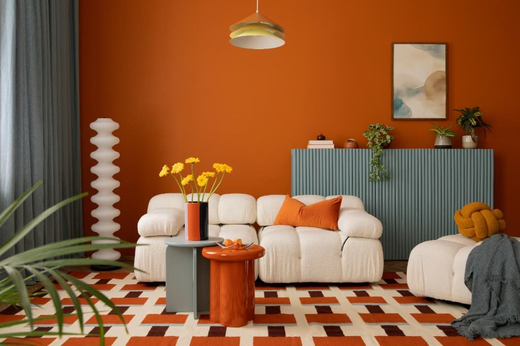 Warm, cosy living room with an orange feature wall, cream sofa and houseplants